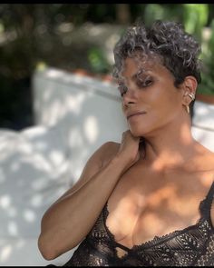 a woman with short hair wearing a black bra and posing in front of a white couch