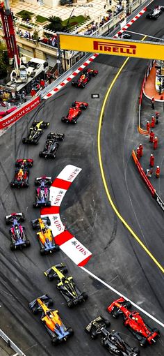 an aerial view of a race track with many cars on it and people standing around