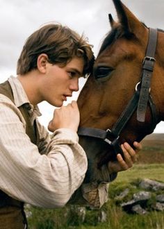 a man standing next to a brown horse