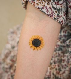 a small sunflower tattoo on the arm