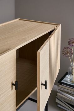 a wooden cabinet sitting next to a glass vase filled with flowers