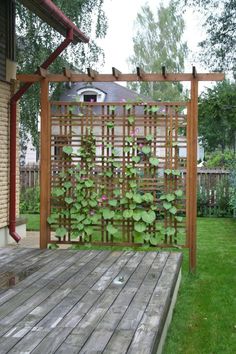 a wooden deck with a trellis and flowers growing on the wall next to it