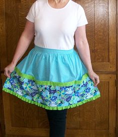 a woman standing in front of a wooden door wearing a skirt with flowers on it