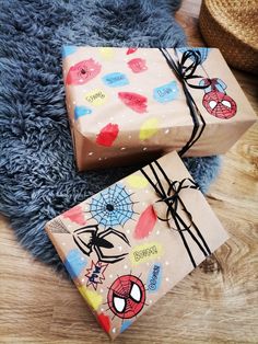 two wrapped presents sitting on top of a wooden floor next to a blue rug with spiderman designs