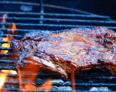 a steak is cooking on the grill with flames coming out of it's sides