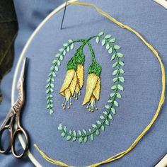 a pair of scissors sitting on top of a piece of cloth next to some embroidery