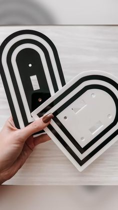 two black and white plates being held by a person's hand on a wooden surface