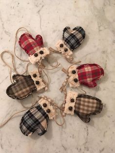 six small plaid heart ornaments on a marble counter top with twine cord and burlap