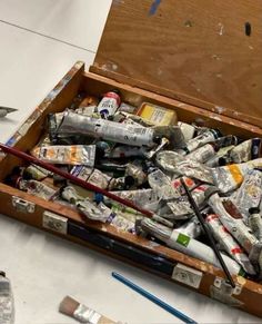 a wooden box filled with lots of different types of paint and pencils on top of a table