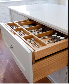 an open drawer with utensils and spoons in it on a kitchen counter