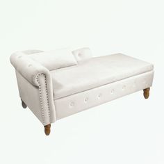 a white leather couch with wooden legs and nail polishing on the armrests