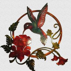 a metal hummingbird with red flowers and leaves on it's side, flying through the air