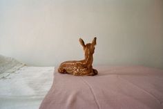 a deer figurine sitting on top of a bed next to a white wall