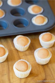 small cupcakes sitting on top of a wooden table next to a muffin tin