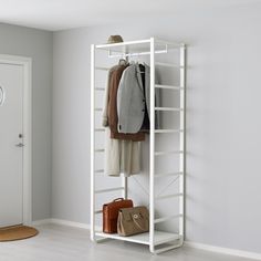 a white coat rack with two coats and purses hanging on the wall next to it