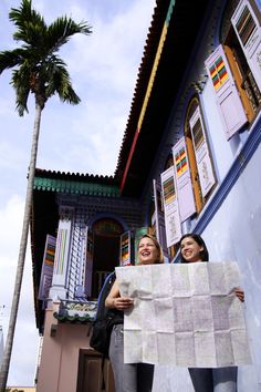 two women standing next to each other holding a newspaper