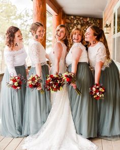 a group of women standing next to each other in front of a wooden building holding bouquets