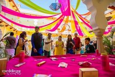 a group of people standing in front of a table covered with pink and yellow cloths