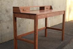 a wooden desk sitting on the side of a building next to a cement wall and concrete floor