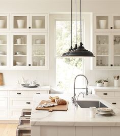 a kitchen filled with lots of white cupboards and counter top next to a sink