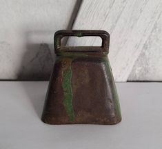 an old brown and green vase sitting on top of a white tablecloth covered floor