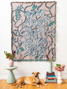 a dog laying on the floor in front of a wall hanging with books and vases