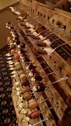 a wooden rack filled with lots of different types of doughnuts on skewers