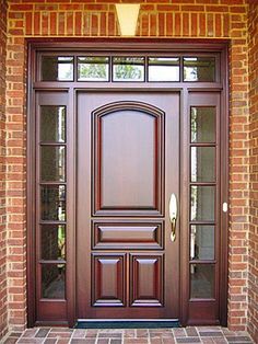 the front door is made of wood and has two sidelights on each side, along with brick