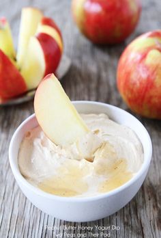 an apple dip in a white bowl with apples around it on a wooden table top