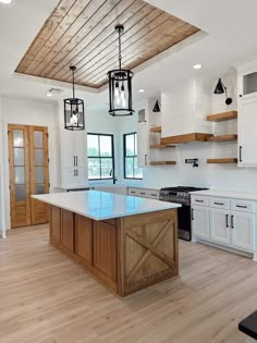 a large kitchen with white cabinets and wood flooring on the walls, along with an island in the middle