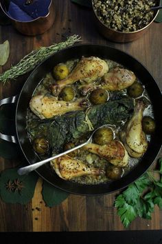 a pan filled with chicken and vegetables on top of a wooden table next to other dishes