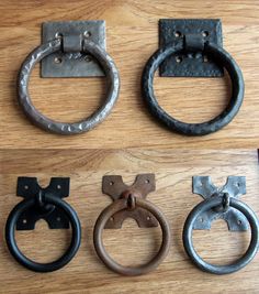 four different types of door handles on a wooden surface with metal rings and hooks attached to them