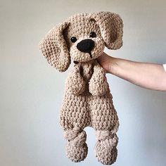 a crocheted stuffed dog is being held by someone