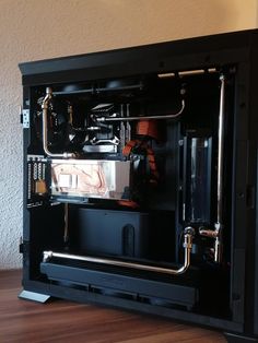 the inside of a black computer case sitting on top of a hard wood floor next to a wall