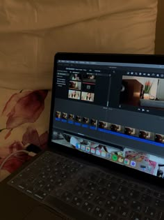 an open laptop computer sitting on top of a bed next to a flowered pillow