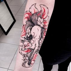 a person with a tattoo on their arm holding onto a red and black fox head