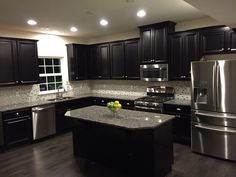 a kitchen with black cabinets, stainless steel appliances and granite counter tops is pictured in this image