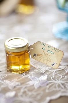 a jar of honey sitting on top of a lace tablecloth with a tag that says love is sweet as honey