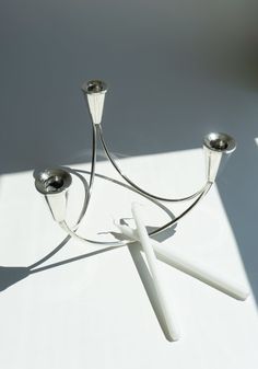 two silver candlesticks sitting on top of a white table next to each other