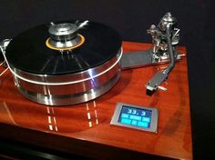 an old record player sitting on top of a wooden table next to a digital clock