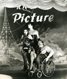 an old photo of three women on a wheel chair in front of a stage curtain