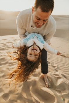 a man and woman playing in the sand with their hands on top of each other