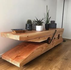 a wooden table with some plants on top of it and a potted plant next to it