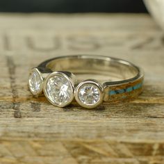 three diamond rings sitting on top of a piece of wood next to a white and blue stone