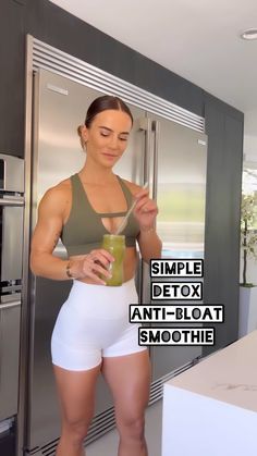 a woman standing in front of a refrigerator holding a drink