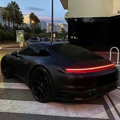 a black sports car is parked in front of a building with palm trees behind it