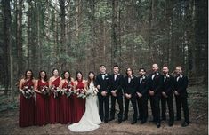 a group of people standing in front of trees wearing red and black outfits with bouquets