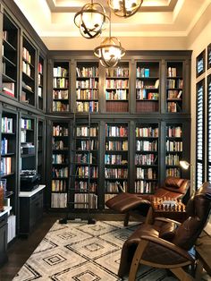 a room filled with lots of books and leather chairs in front of a book shelf