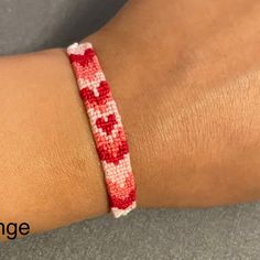 a close up of a person's arm wearing a bracelet with red and white beads