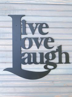 a metal sign that says live love laugh on the side of a white wooden wall